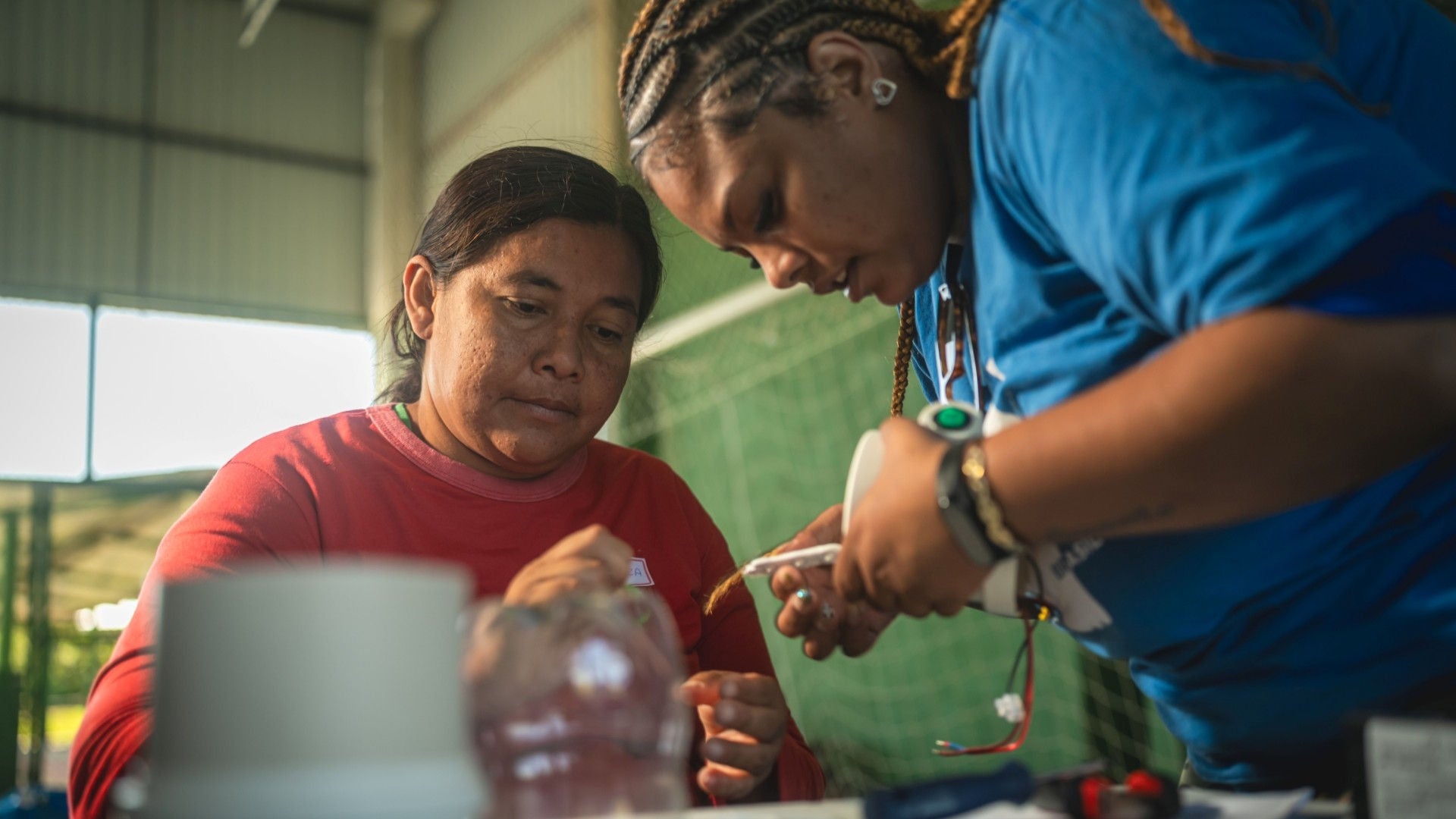 2 women building a solar lamp.